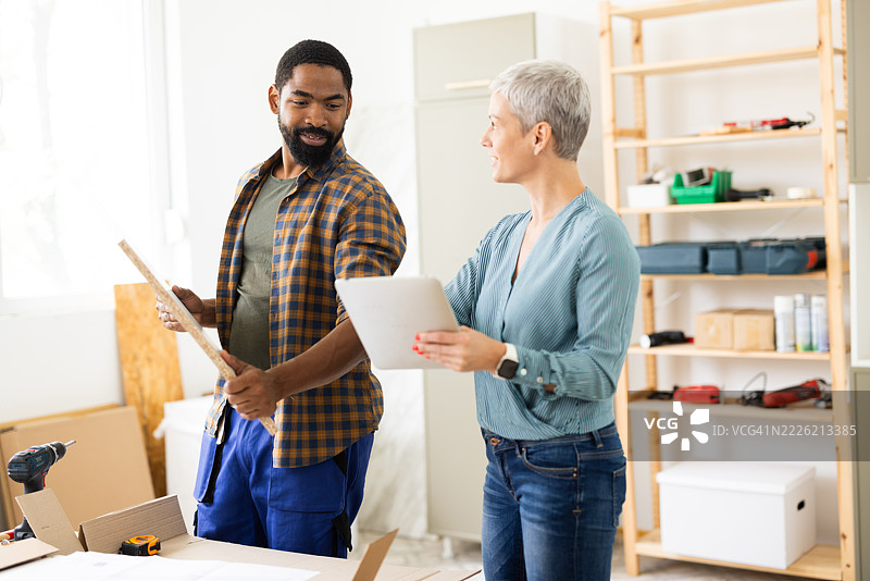 木匠在家居装修期间向建筑师展示木板，建筑师使用数字平板电脑。图片素材