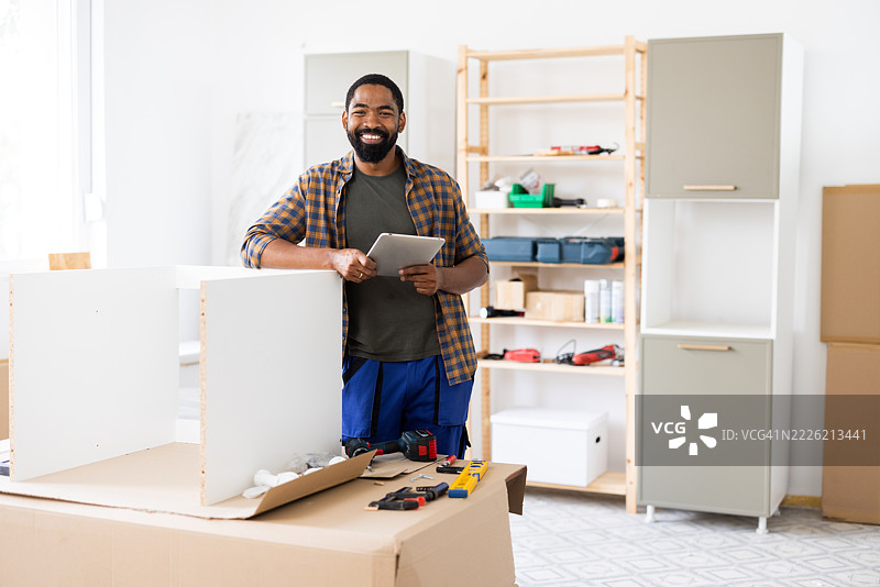 快乐的木匠在他的工作坊里使用平板电脑组装家具图片素材