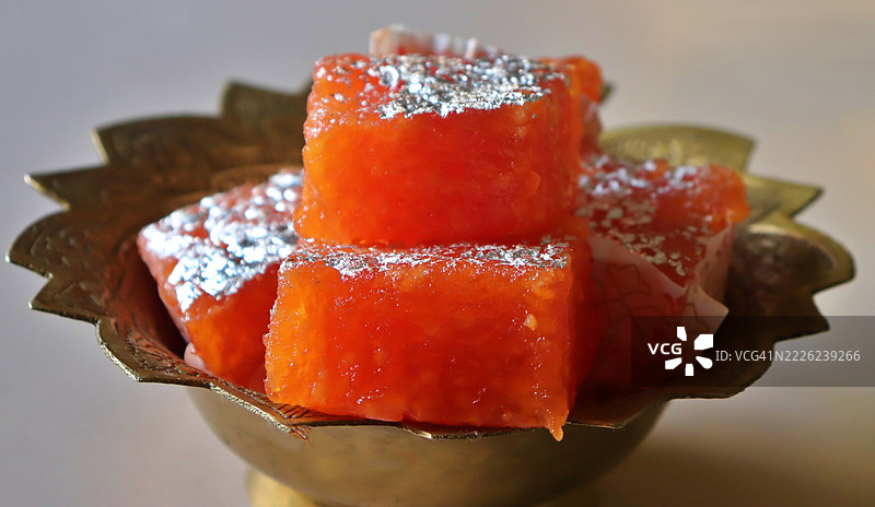 铜碗中的纳格普尔橙色奶糖特写/白色背景/静物摄影图片素材