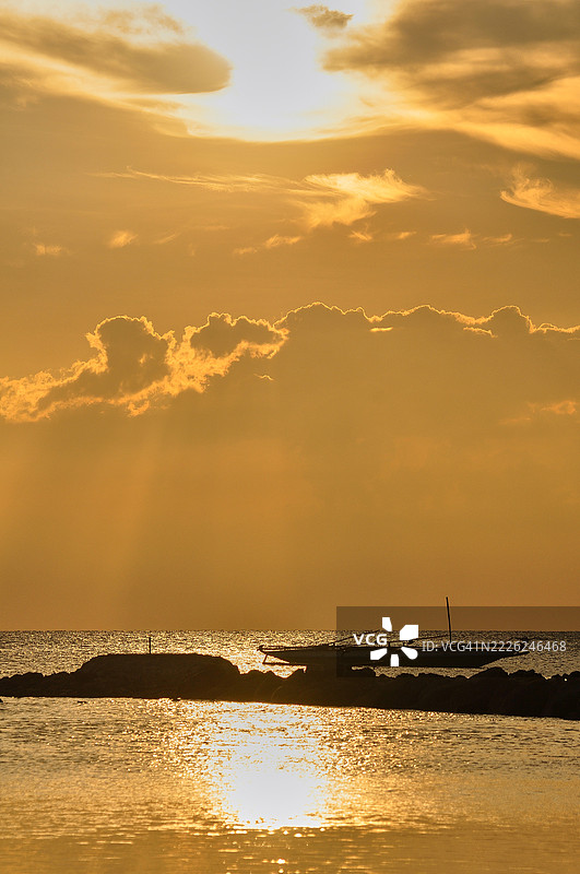 五彩斑斓的日落照亮了天空，温暖的橙色和红色映衬在一片大水面上。图片素材