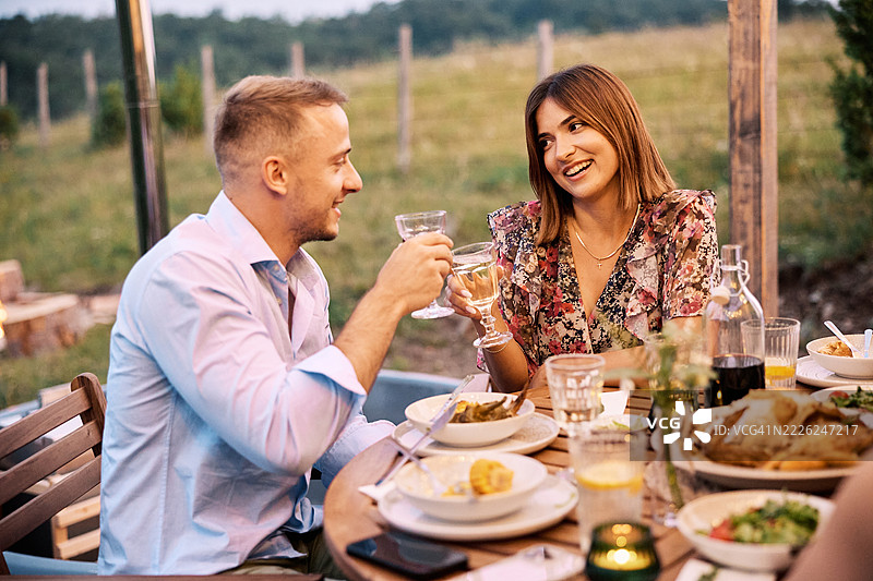 微笑的朋友们在户外享用白葡萄酒并祝酒图片素材