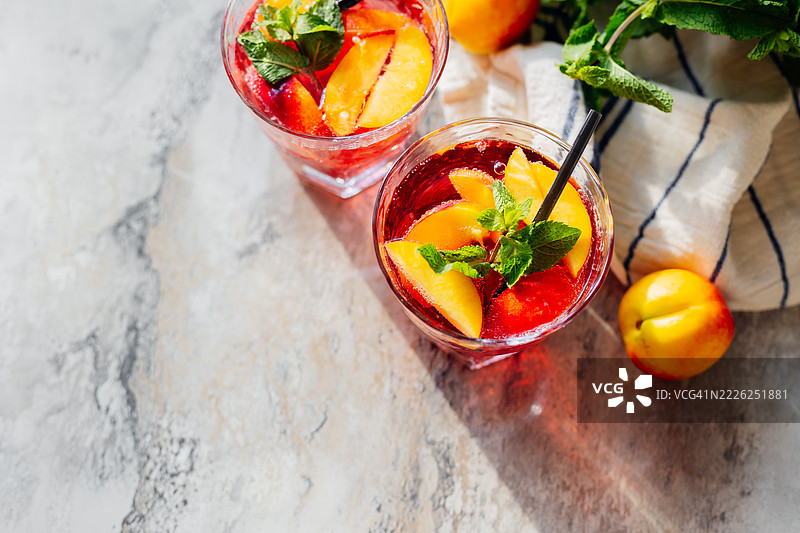 夏季冷桃鸡尾酒或薄荷冰茶，背景为大理石。自制水果冰茶，顶部视角，留有空白空间。图片素材