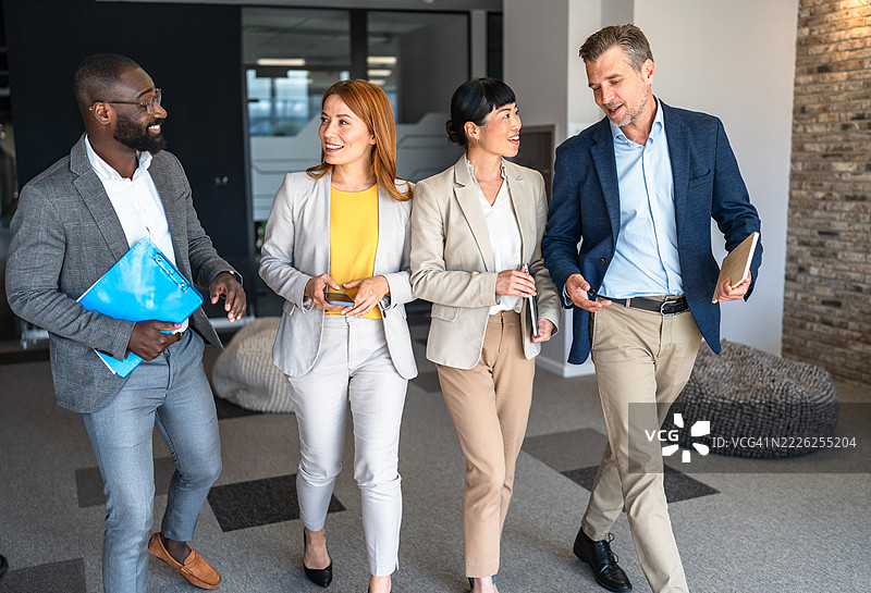 商务人士在办公室走廊里走动并交谈图片素材