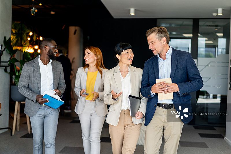 商务人士在办公室走廊中走动并交谈图片素材