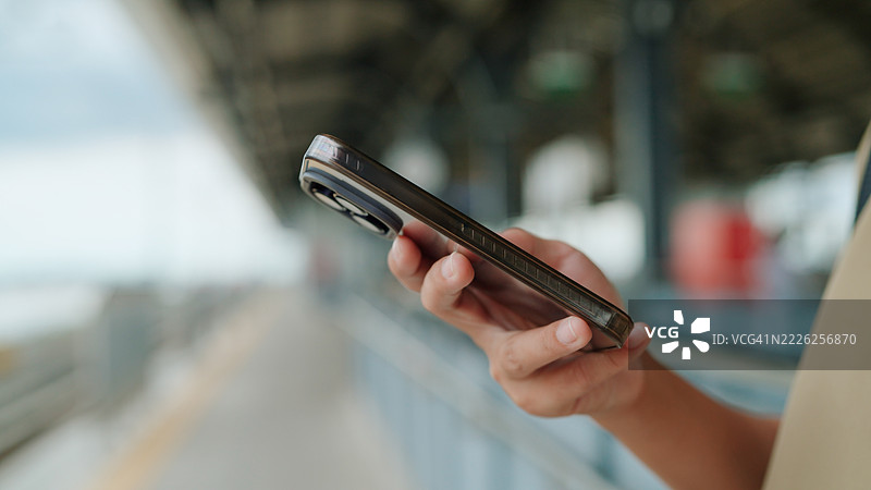 亚洲女性在站台上等火车时使用人工智能应用程序图片素材