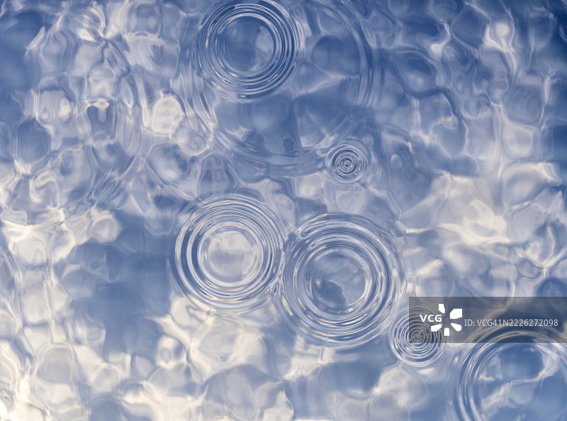 全景，雨滴落下，在泳池的水面上产生同心圆的涟漪。图片素材