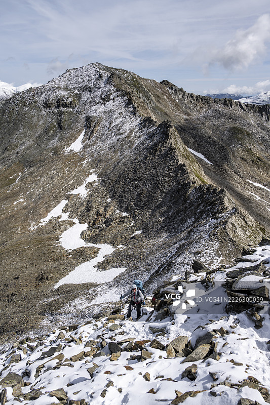 夏季在多石地貌上,覆盖着新雪的登山者,攀登博塞维布尔峰,维也纳高地步道,绍伯尔山脉,霍赫陶恩国家公园,卡林西亚,奥地利图片素材