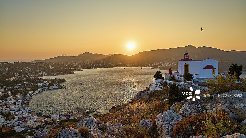 伊利亚斯教堂,浪漫的教堂场景坐落在山丘上,俯瞰日落时分的海湾,飞翔的鸟,阿尔金塔斯港,阿吉亚玛丽娜,莱罗斯,多德卡尼斯,希腊群岛,希腊图片素材