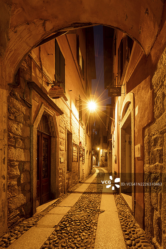 夜间照亮的小巷，意大利皮埃蒙特大区诺瓦拉省奥尔塔湖畔的奥尔塔圣朱利奥古镇中心图片素材