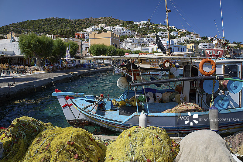 希腊岛屿，德德卡尼斯，莱罗斯，阿吉亚玛丽娜，一个希腊村庄的港口里停着渔船，周围是渔网和蓝天。图片素材