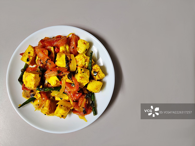 简单的奶酪咖喱，配有番茄、青辣椒和洋葱，放在白色陶瓷盘中/白色背景/静物摄影图片素材