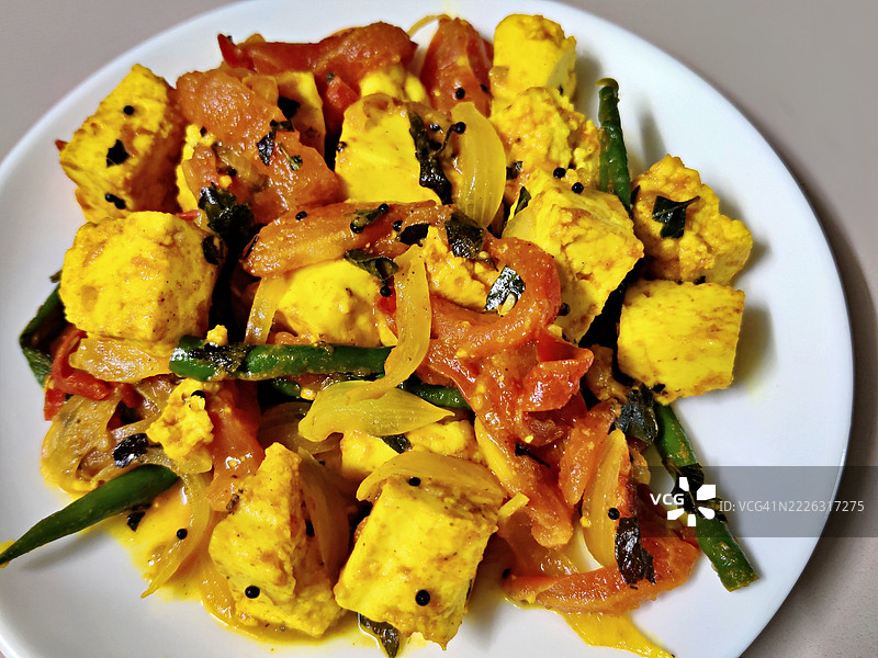 简单的奶酪咖喱，配有番茄、青辣椒和洋葱，盛放在白色陶瓷盘中/白色背景/静物摄影图片素材