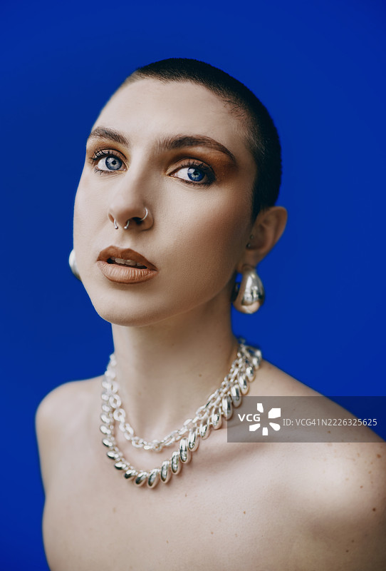 身穿银色首饰的自信女性，背景为蓝色图片素材