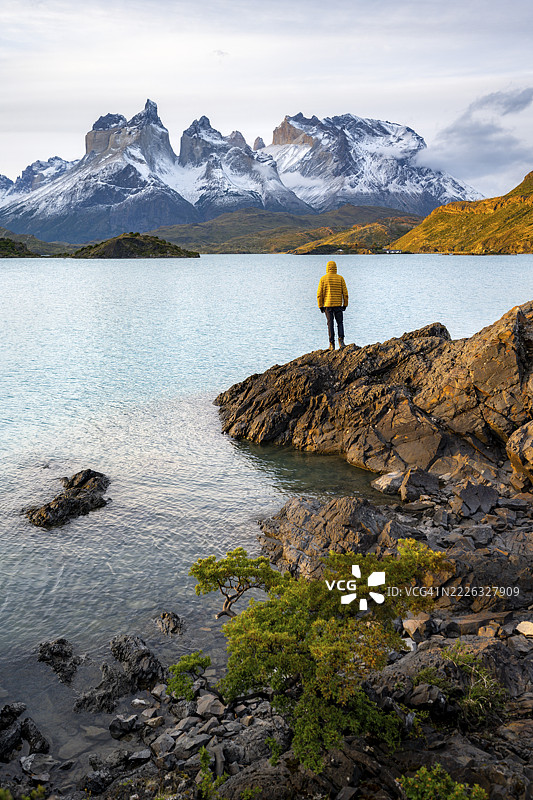 夕阳下的佩霍湖畔,库埃诺斯德尔帕内山脉,百内国家公园,智利,一位年轻男子伫立岸边图片素材