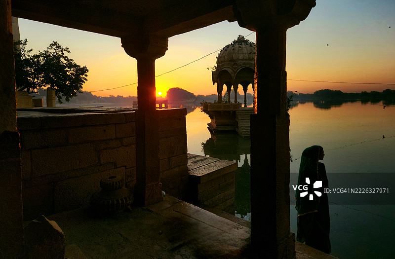 穿着纱丽的印度女性在拉贾斯坦邦杰沙梅尔的加迪萨尔湖观看日出图片素材