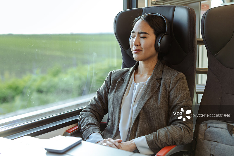 女商人在火车旅行中戴着耳机放松。图片素材