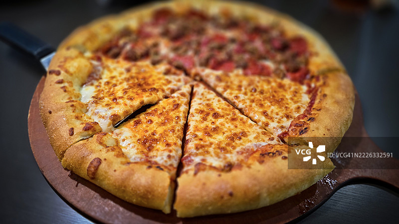美味的比萨，配有奶酪和肉类爱好者的浑合配料，放在木板上。金黄色的奶酪填充边，AR，必胜客，906 E Beebe Capps Expy，Searcy，72143，美国图片素材