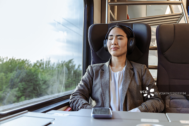 女商人在火车旅行中戴着耳机放松。图片素材