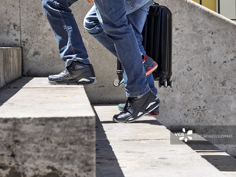 两个年轻游客匆忙地提着手提箱上楼梯。图片素材