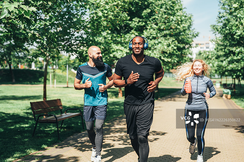 一群朋友在阳光明媚的日子里一起在公园慢跑图片素材