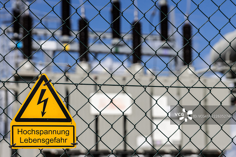高压警告标志，背景为电力变压器站的绝缘设施图片素材