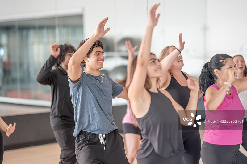 明亮的健身工作室中，参与者多样的团体健身课程图片素材