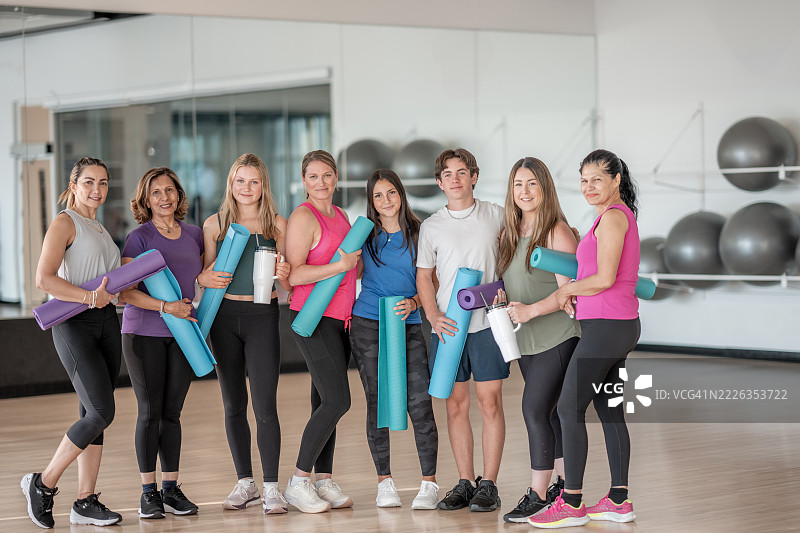 一群人在健身工作室里微笑着手持瑜伽垫图片素材