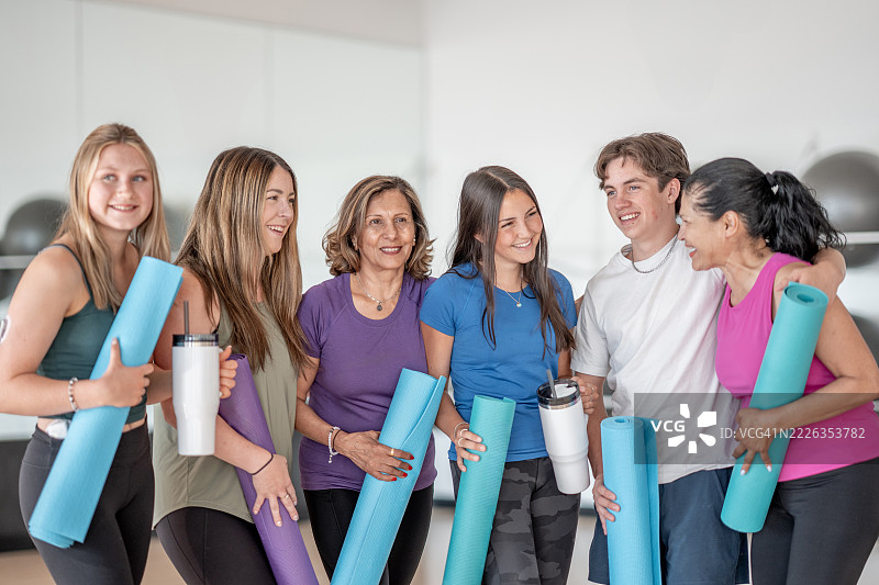 一群朋友在健身环境中微笑，手持瑜伽垫图片素材