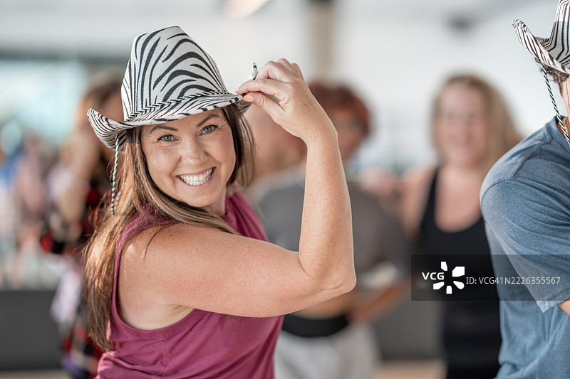 微笑的女性戴着斑马帽子与朋友们在室内活动中跳舞图片素材