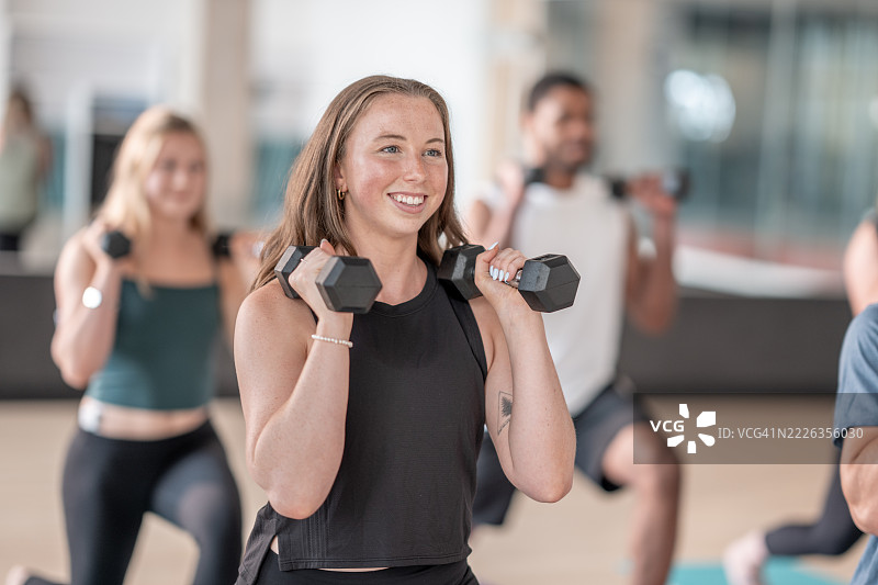 健身房内参与者举着哑铃的团体力量训练课程图片素材