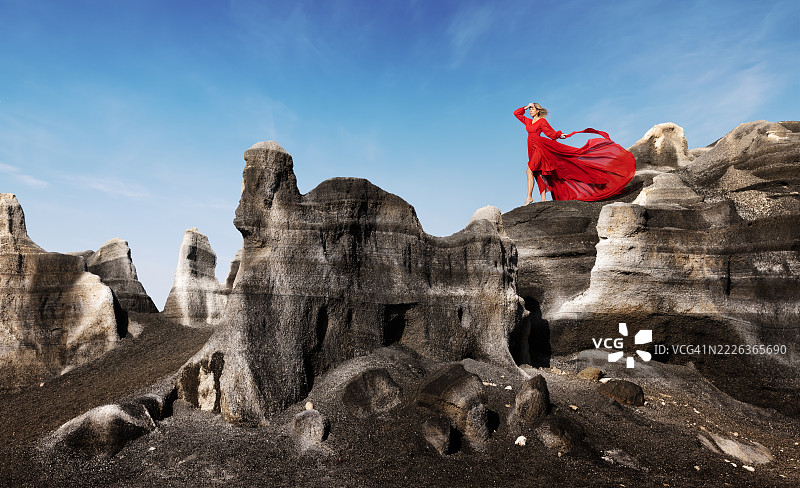 低角度视图的女性坐在岩石形成物上，背景是天空，瓦列塞科，西班牙，加纳利群岛图片素材