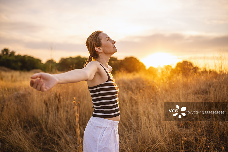 女人怀着感激之情享受日落图片素材