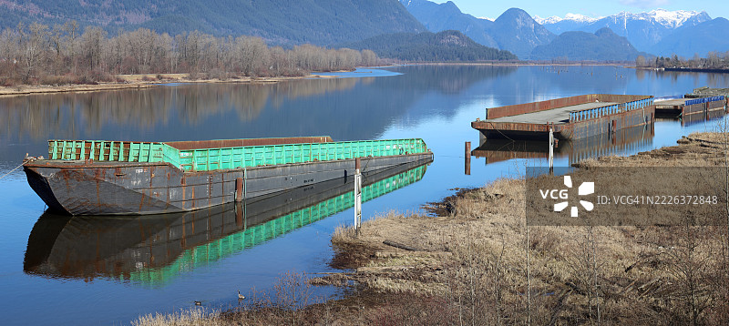 在宁静的河流上停泊的沉没驳船，加拿大不列颠哥伦比亚省皮特梅多斯图片素材