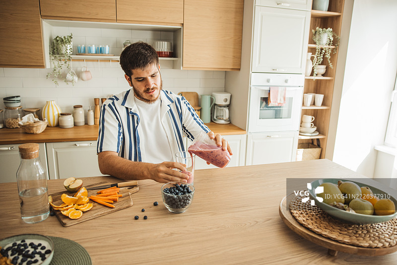 年轻男子在厨房制作蓝莓奶昔图片素材