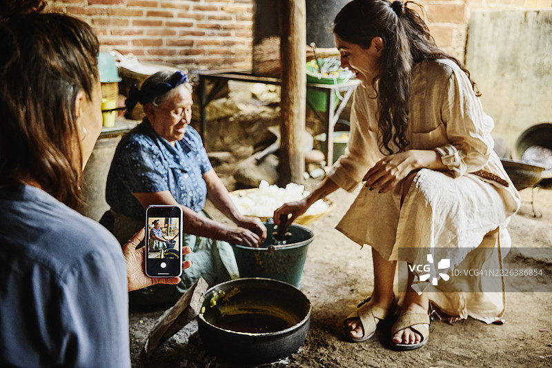中景拍摄的女性游客正在为制作蜡烛的朋友拍照图片素材