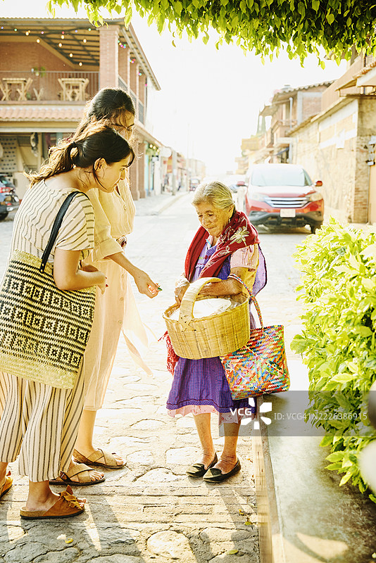 女性朋友们在街头小吃摊购买玉米饼的广角镜头图片素材