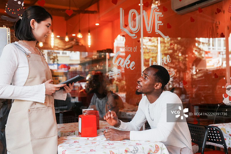 一位年轻的女服务员正在使用数字平板电脑为顾客点餐。图片素材