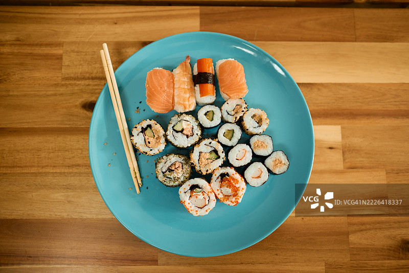 美味的寿司拼盘放在浅蓝色盘子上，旁边有筷子图片素材