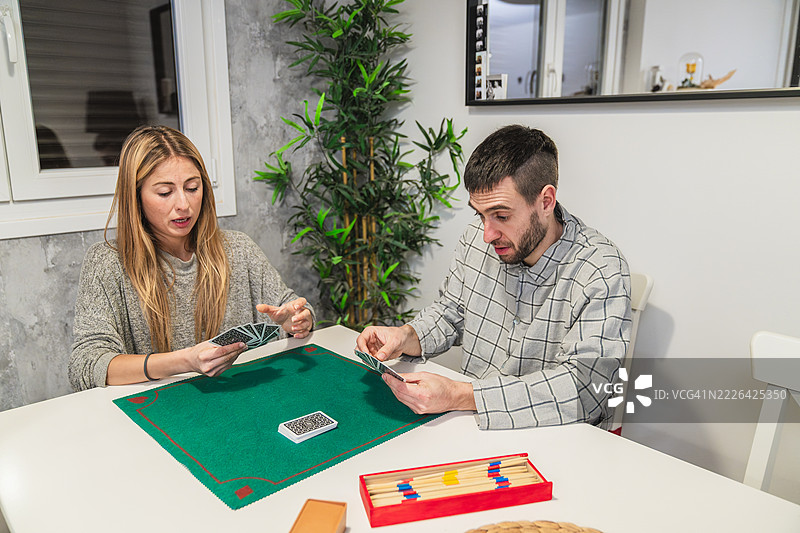 年轻情侣在绿色地毯上玩牌图片素材