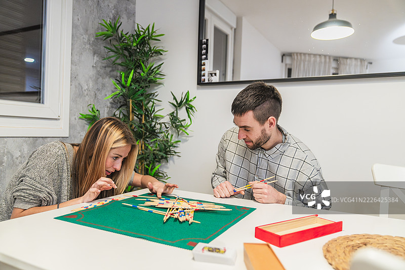 年轻情侣在家玩拾棒游戏图片素材