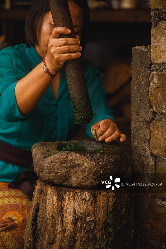 在乡村环境中用石臼研磨草药的女人图片素材