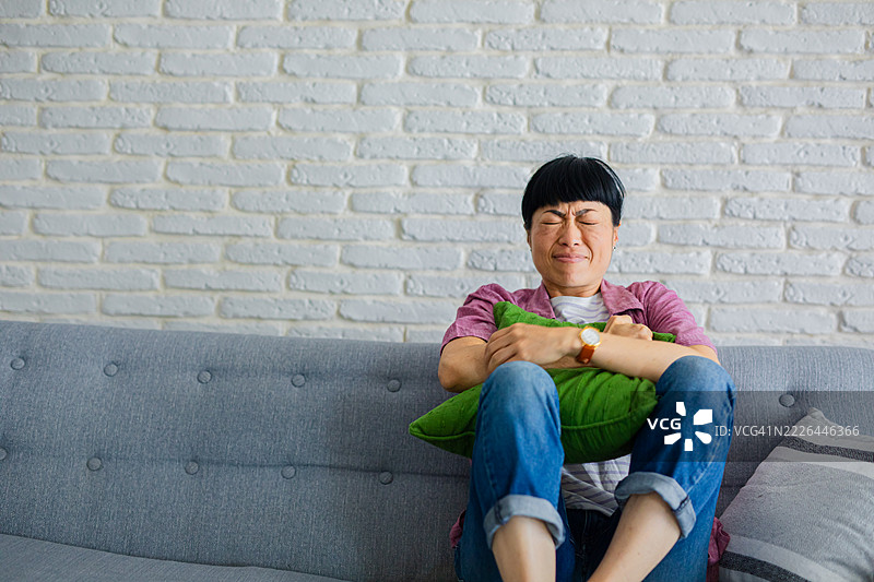 坐在沙发上的女性感到腹痛图片素材