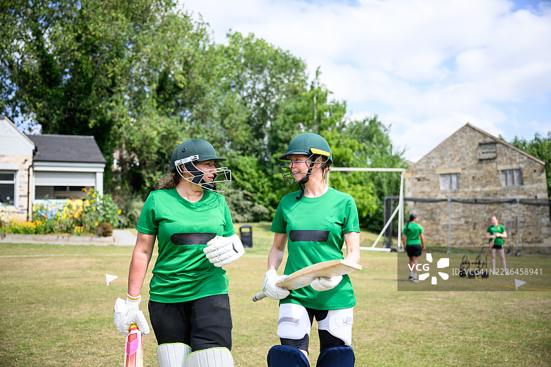 正面视角的女子击球队穿着保护性运动服走向场地，准备击球图片素材
