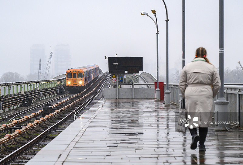 橙色地铁列车在雨天抵达基辅地铁桥站图片素材