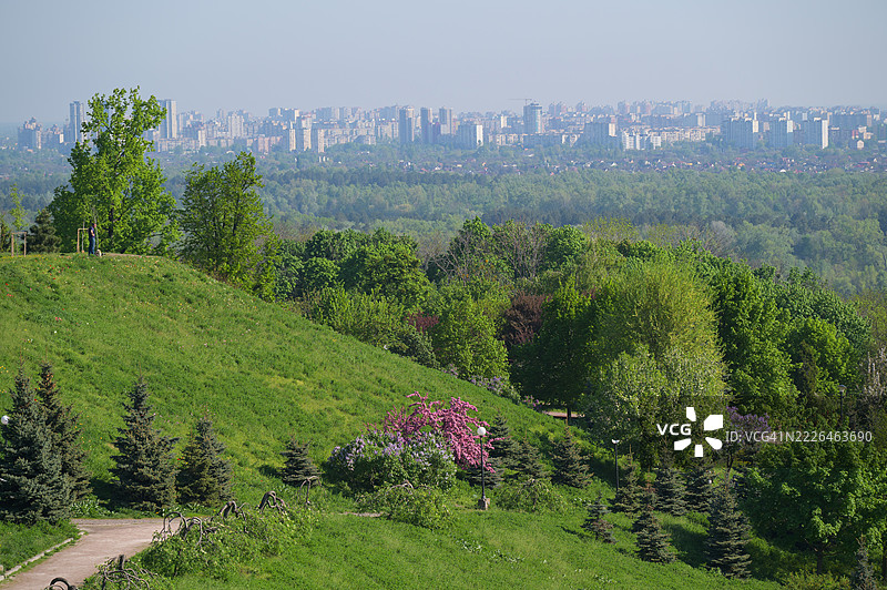 游客在春天的绿丘上欣赏基辅的城市风景图片素材