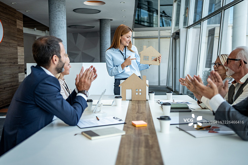 房地产经纪人向同事展示纸板房屋图片素材