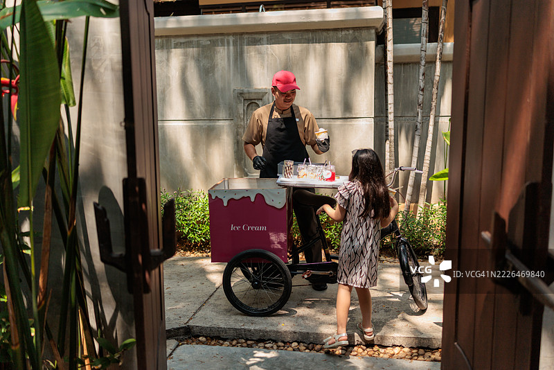 当地泰国冰淇淋商贩正在把冰淇淋递给小女孩图片素材