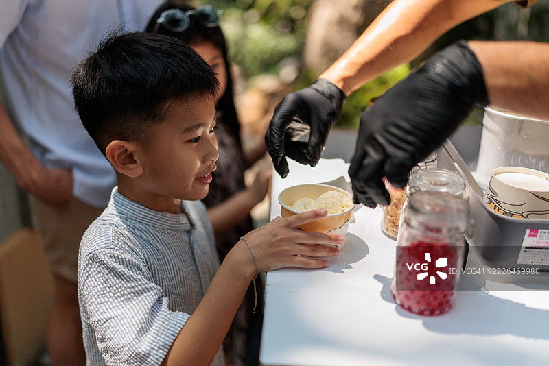 兴奋的小男孩正在接过他的冰淇淋杯图片素材
