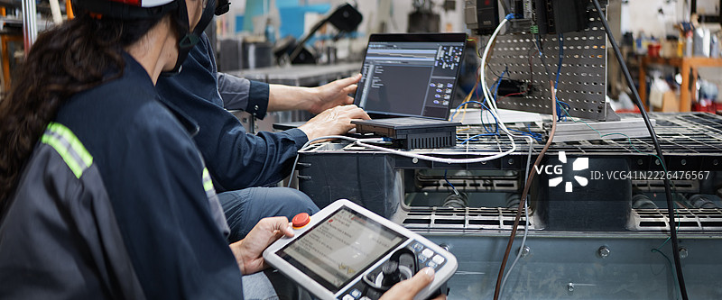 白人工业工程师男女在机器人工厂使用笔记本电脑和平板控制电动机器。机械工业工程业务。蓝领工人，科技概念。图片素材