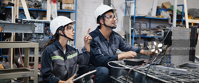 白人拉丁裔工业工程师男女在机器人工厂一起操作电动机器。机械工业工程业务。蓝领工人，科技职业生活方式概念。图片素材
